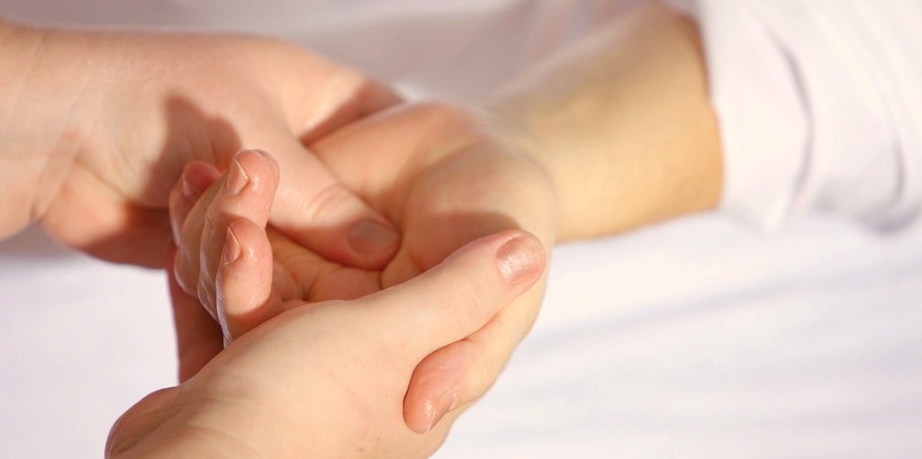 Le mani di un'estetista al lavoro su quelle di una cliente